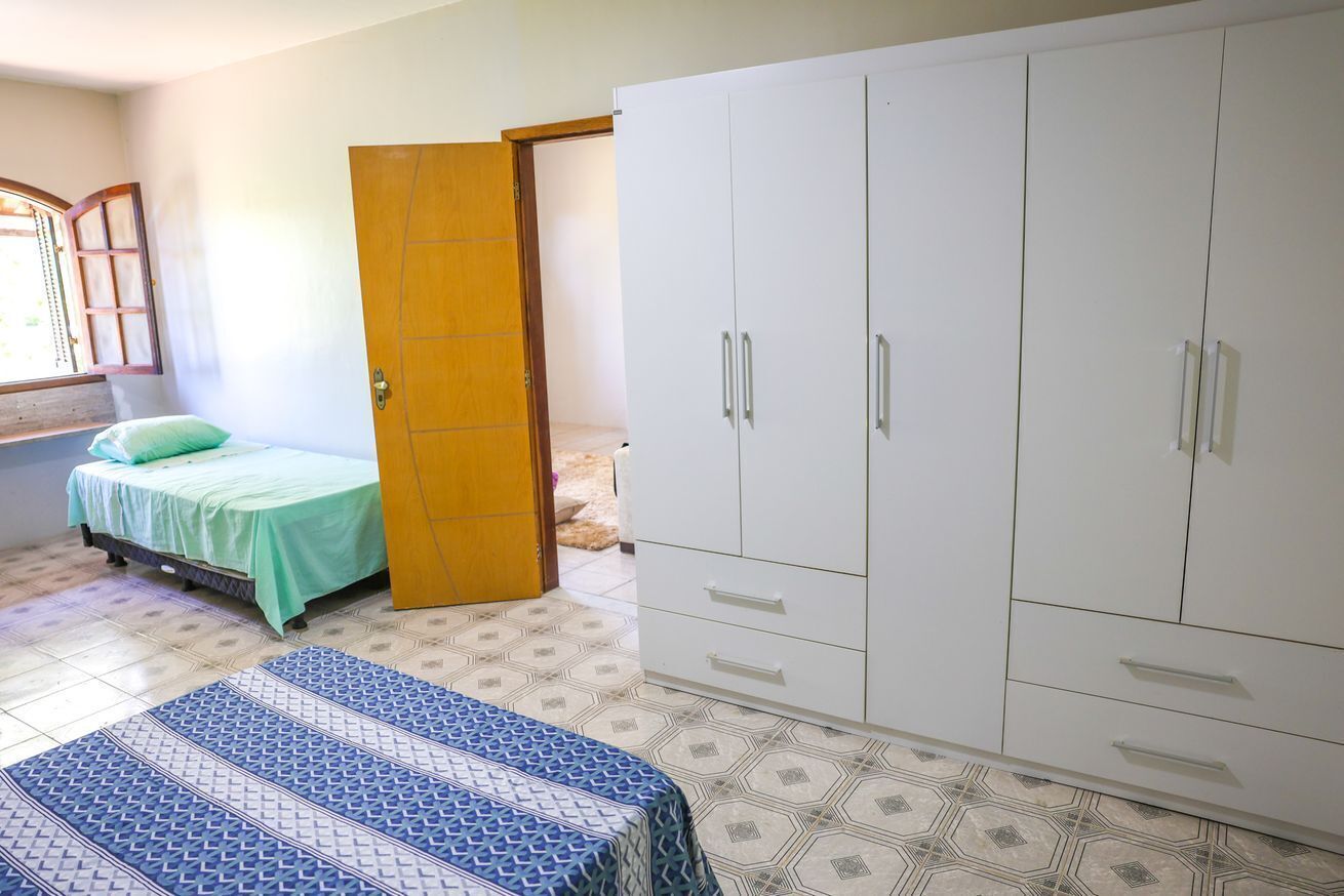 Ein Schlafzimmer mit Bett, Kleiderschrank und einem Fenster mit Vorhängen.