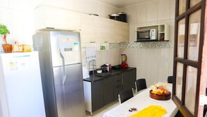 Una cocina compacta con refrigerador, microondas y una mesa de comedor con sillas.