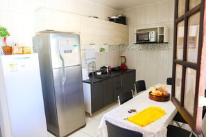 Eine kleine Küche mit Kühlschrank, Mikrowelle und einem Esstisch mit Stühlen.