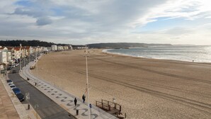 Una strada costiera con una spiaggia a destra, fiancheggiata da edifici.