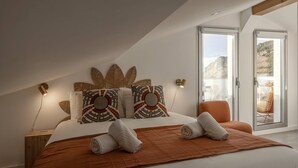 Una camera da letto moderna con un letto grande, cuscini fantasia, una coperta marrone e vista sull'esterno tramite una porta scorrevole.