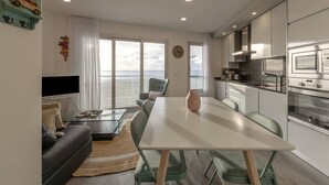 Un soggiorno moderno con zona pranzo, cucina e ampie finestre vista mare.