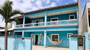 Ein zweistöckiges Gebäude mit blauer Fassade, einem Balkon im oberen Stockwerk und einer Hängematte an der Seite.