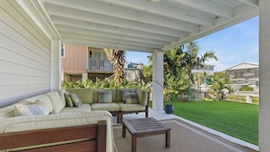 A covered outdoor seating area with a sofa and a coffee table, a well-maintained lawn, and a view of neighboring buildings. - Hooked on Avocado -Stunning 5 Bedroom/ 3 Bath waterfront home on canal, resort style private pool & hot tub, 34’ dock, and quick open-water Gulf and Atlantic access. Ice Maker, Ping Pong table. Minutes to Sombrero Beach & Dining. (Marathon)