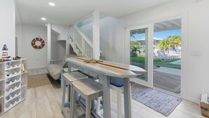 A modern interior with a staircase, a dining area with benches, a shelf with bottles, and a view of the outdoors. - Hooked on Avocado -Stunning 5 Bedroom/ 3 Bath waterfront home on canal, resort style private pool & hot tub, 34’ dock, and quick open-water Gulf and Atlantic access. Ice Maker, Ping Pong table. Minutes to Sombrero Beach & Dining. (Marathon)