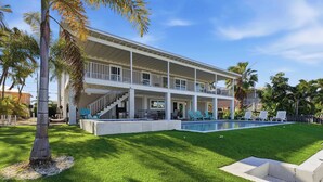 A two-story house with a swimming pool, a covered patio, and a well-maintained lawn. - Hooked on Avocado -Stunning 5 Bedroom/ 3 Bath waterfront home on canal, resort style private pool & hot tub, 34’ dock, and quick open-water Gulf and Atlantic access. Ice Maker, Ping Pong table. Minutes to Sombrero Beach & Dining. (Marathon)