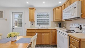 A compact kitchen with wooden cabinets, a white stove, and a microwave. - The Bungalow 1 Bed / 1 Bath Duplex Near Vanderbilt Beach (Naples)