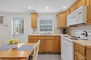 Une cuisine de taille réduite, avec des meubles de rangement en bois, une cuisinière blanche et un four à micro-ondes.