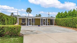 A two-story building with a covered patio area, surrounded by well-maintained hedges and a clear sky. - The Bungalow 1 Bed / 1 Bath Duplex Near Vanderbilt Beach (Naples)