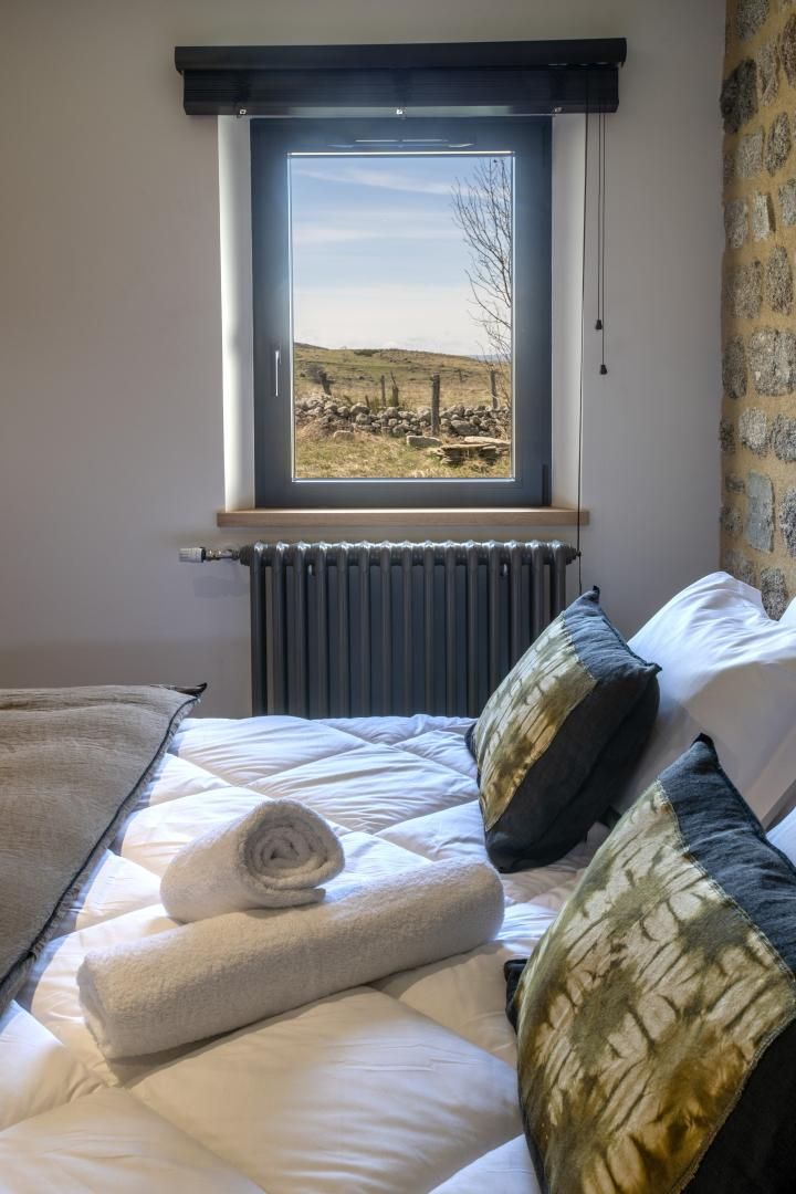 A bedroom with a bed, a window with a view of a landscape, and a radiator.