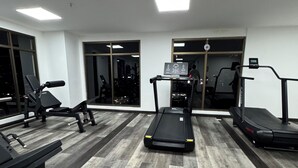 Ein Fitnessstudio mit Laufbändern, Krafttrainingsgeräten und einer Spiegelwand.