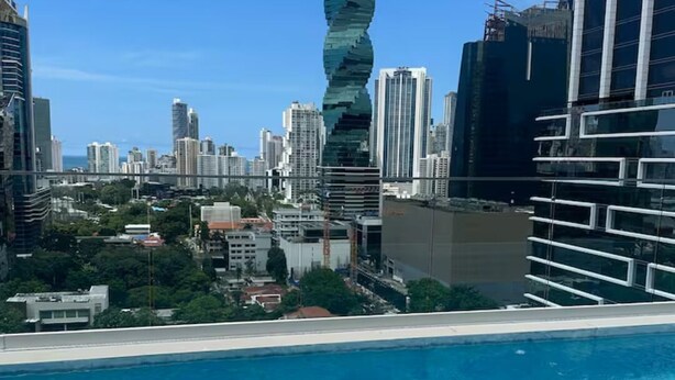 Ein Schwimmbad mit Stadtblick, darunter moderne Gebäude und ein markanter Wolkenkratzer.
