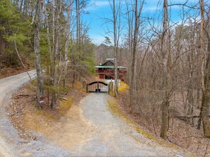 A gravel driveway leading to a gated entrance with a house in the background. - Smoky Mtn Cabin w Hot Tub & Game Room! (Sevierville)