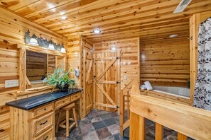 Ein Interieur einer Holzhütte mit Badezimmer, Waschbecken, Spiegel, Telefon und Duschbereich.