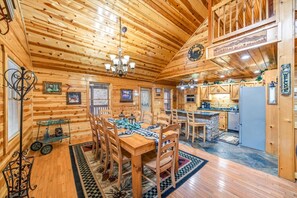 A log cabin interior with a dining area, kitchen, and a chandelier. - Smoky Mtn Cabin w Hot Tub & Game Room! (Sevierville)
