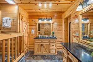 Une salle de bain rustique, avec une cabine en bois, un meuble-lavabo en bois, un miroir et un porte-serviettes.