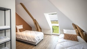 Une chambre avec un plafond en pente, un lit en mezzanine et un puits de lumière.
