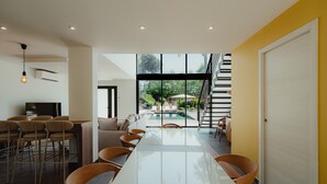 Un intérieur moderne comprenant un coin repas, une cuisine et une vue sur une piscine et un espace extérieur.