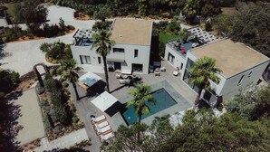 Une maison moderne à deux étages, dotée d’une piscine, d’un espace de détente extérieur et d’un jardin bien entretenu.