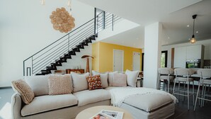 Un salon moderne avec un canapé, une table basse et un escalier menant à un niveau supérieur.
