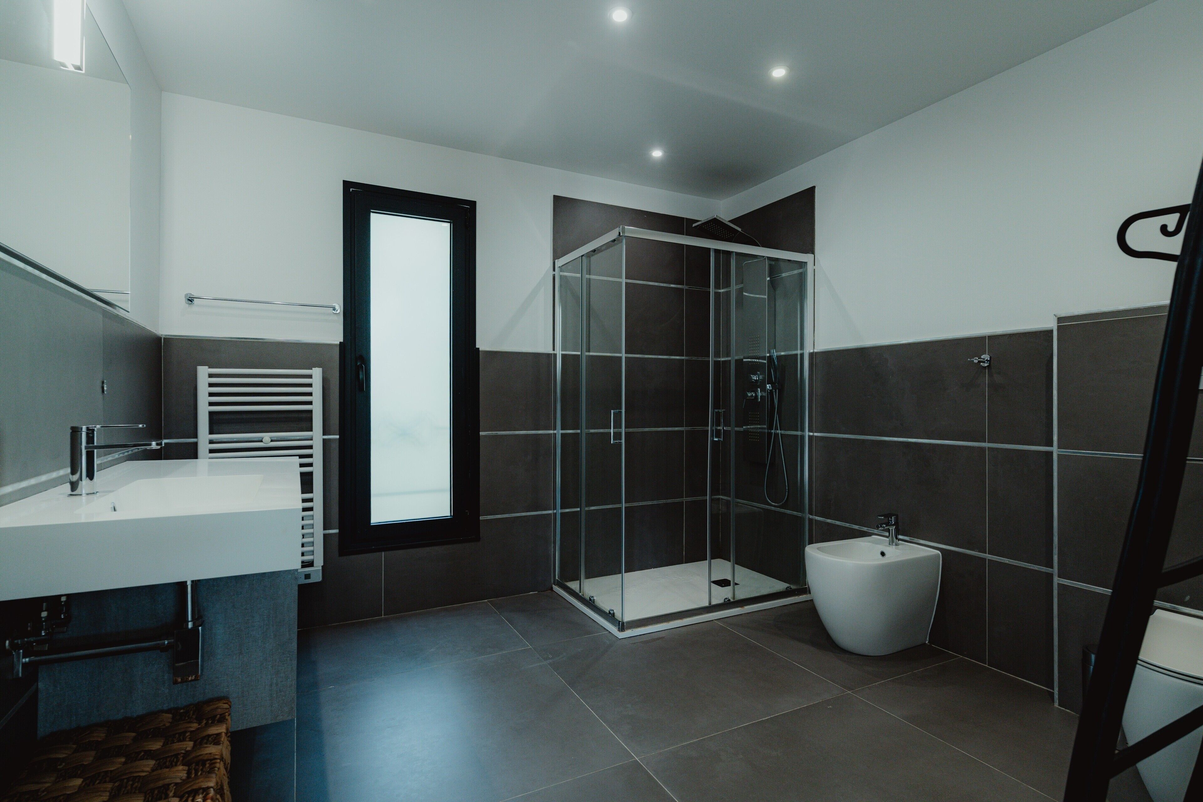 Une salle de bain moderne dotée d’une douche à parois de verre, d’un bidet et d’un grand miroir.