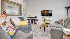Ein modernes Wohnzimmer mit grauen Sofas, einem Couchtisch, einem Fernseher und einem Essbereich mit Tisch und Stühlen.