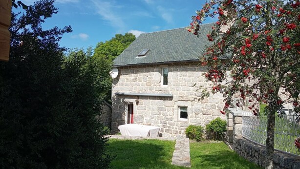 A stone house with a sloped roof, a small porch, and a well-maintained lawn. - L'Oustal de la Fillo (CHAUCHAILLES)