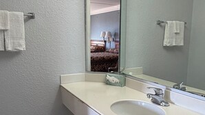 Une salle de bain avec un lavabo blanc, un grand miroir et un sol carrelé.