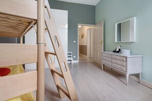 Um quarto com uma cama beliche, uma escada de madeira, uma cômoda e um espelho.