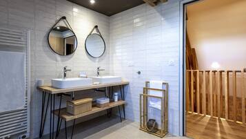 A modern bathroom with two sinks, a mirror, and a wooden bench.