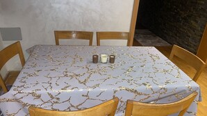 A dining table with a white tablecloth featuring a gold leaf pattern, surrounded by wooden chairs.