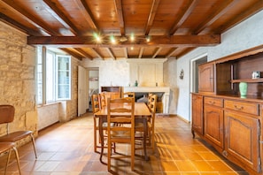 A rustic dining area with a wooden table and chairs, stone walls, and a tiled floor. - Holiday Home 'La Maison Charentaise' with Private Terrace and Wi-Fi (Saint-Simon de Pellouaille)