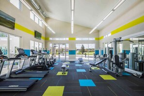 Ein Fitnessstudio mit Laufbändern, Krafttrainingsgeräten und einer Bank.