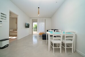 A modern, well-lit room with a dining table and chairs, a television, and a view of the outdoors. - Heli View Apartment with Sea View, Wi-Fi and Air Conditioning (Ermionida)