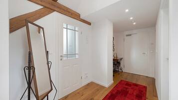 A room with wooden beams, a white door, a red rug, and a white wall.