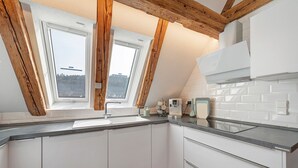 Una cucina con mobili bianchi, un tappeto rosso e vista attraverso un lucernario.