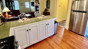 A modern kitchen with a central island, stainless steel appliances, and hardwood flooring. - The Judge's Chambers: Superior King Bed (Prescott)