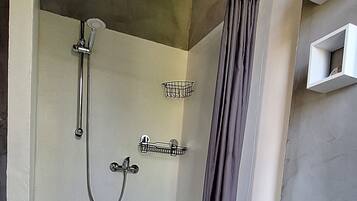 A modern bathroom with a shower, a sink, and a storage cabinet.