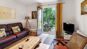 Una sala de estar con un sofá de cuero, una mesa de centro de madera y un televisor.