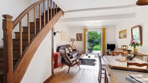 Una escalera conduce a una sala de estar con un sofá, una mesa de comedor y un televisor.