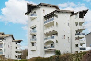 Ein mehrstöckiges Wohngebäude mit Balkonen, einer flachen Dachterrasse und blauem Himmel.