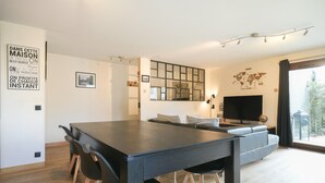 Ett modernt vardagsrum med ett matbord, en soffa och en stor TV.