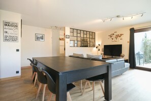 Ett modernt vardagsrum med ett matbord, en soffa och en stor TV.