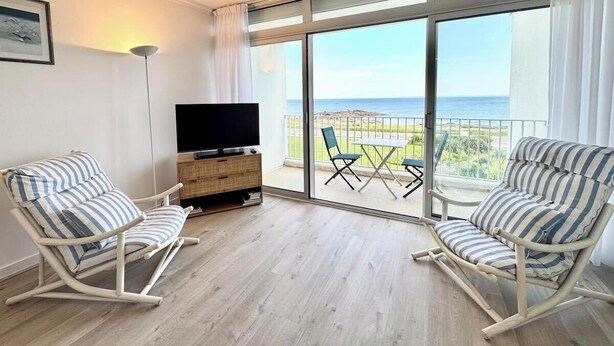 A balcony with a TV, two striped rocking chairs, and a wooden cabinet. - Évasion Marine - Vue mer imprenable 180° (Quiberon)