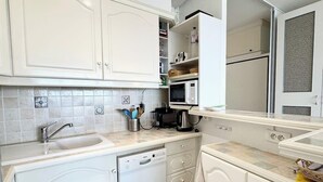 A modern kitchen with white cabinetry, a built-in dishwasher, and a microwave. - Évasion Marine - Vue mer imprenable 180° (Quiberon)