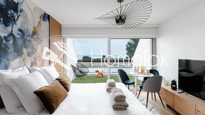 Une chambre d’hôtel moderne avec un grand lit, une télévision et une vue sur la mer.