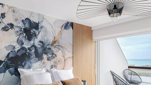 Une chambre à coucher moderne avec un grand lit, une vue sur la mer et un luminaire au plafond original.