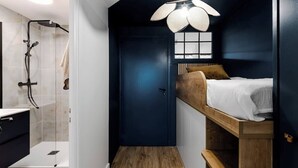 Une chambre à coucher de taille réduite, équipée d’un lit superposé, d’un espace douche et d’un luminaire au plafond original.