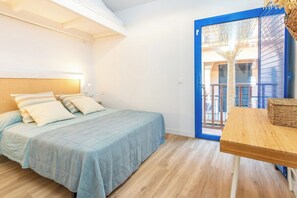 A bedroom with a bed, bedside table, and a view through a blue door. - Casa con encanto a pie de playa (Tamariu)
