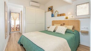 Una camera da letto con un letto, una coperta verde, una trapunta bianca e un pavimento in legno.